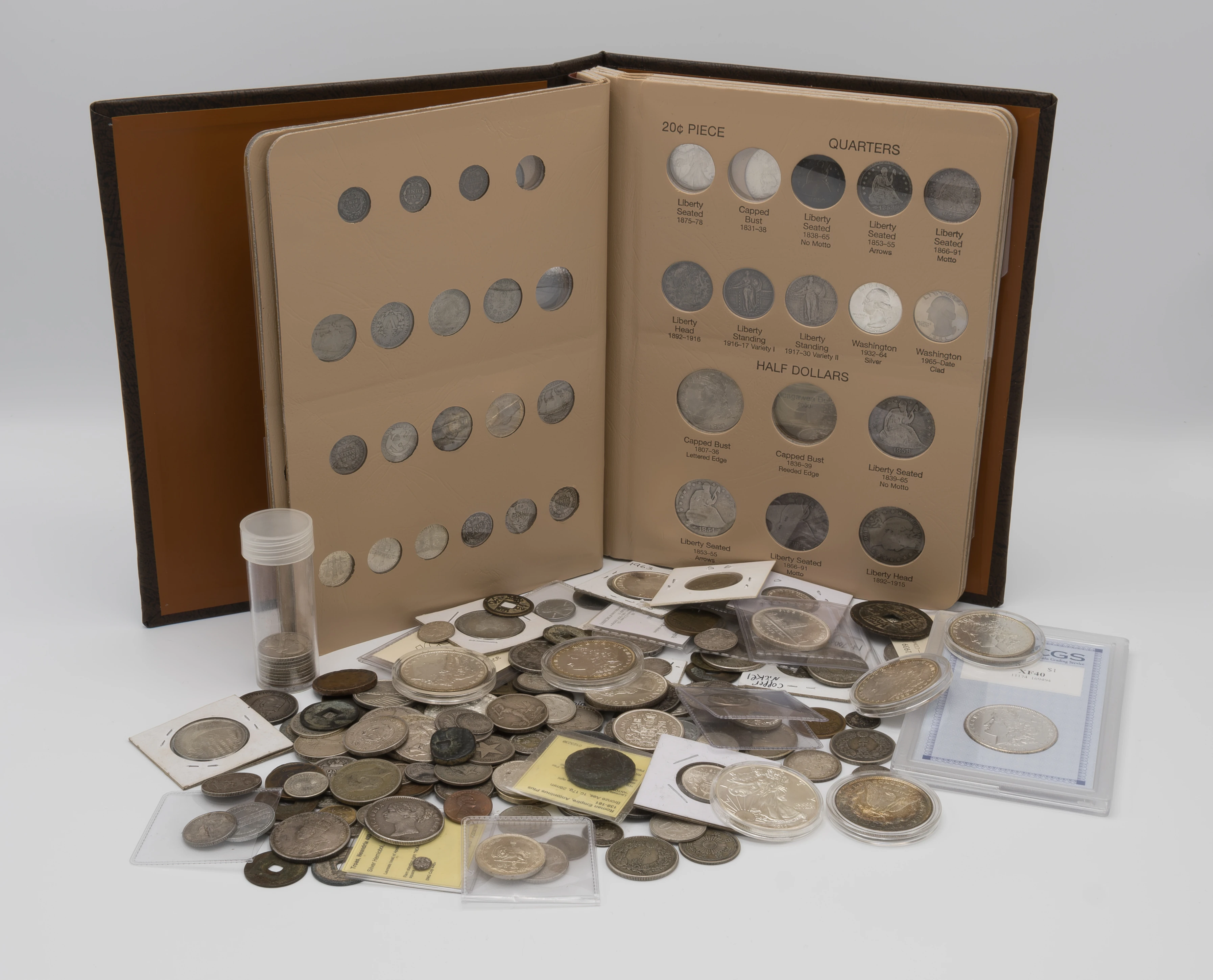 A coin album beside coins in flips, capsules, a tube and a certified holder.