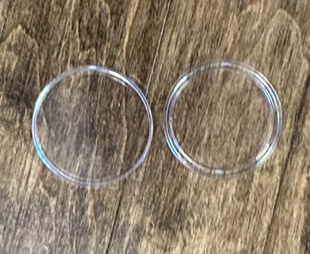 Two clear halves of an empty coin capsule.